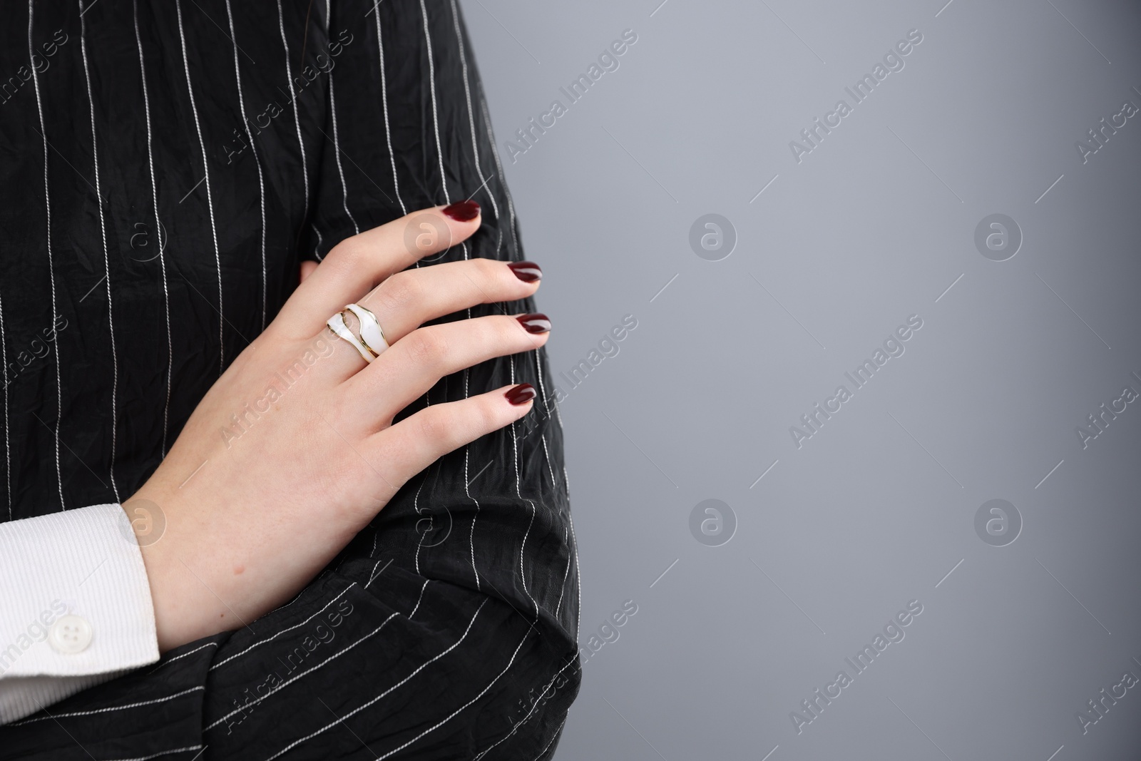 Photo of Teenage girl wearing stylish ring on grey background, closeup. Space for text