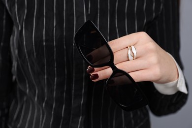 Photo of Teenage girl with sunglasses and stylish ring on grey background, closeup