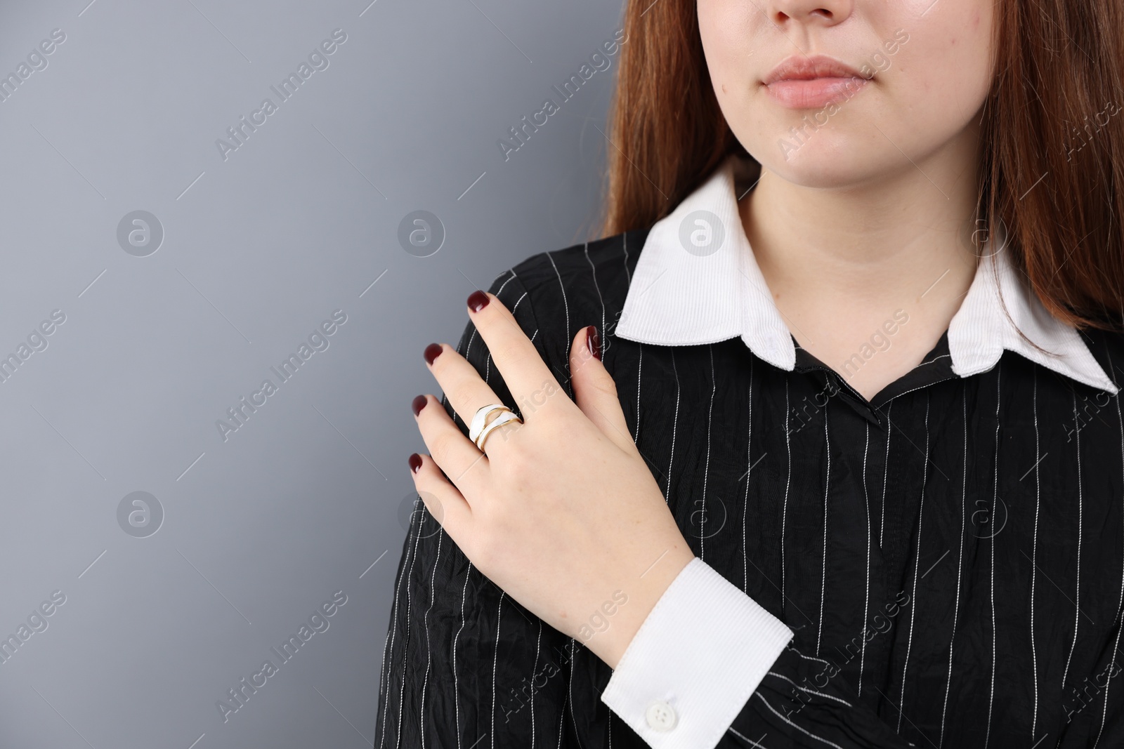 Photo of Teenage girl wearing stylish ring on grey background, closeup. Space for text