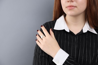 Photo of Teenage girl wearing stylish ring on grey background, closeup. Space for text