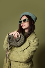 Photo of Young woman with stylish accessories on olive background