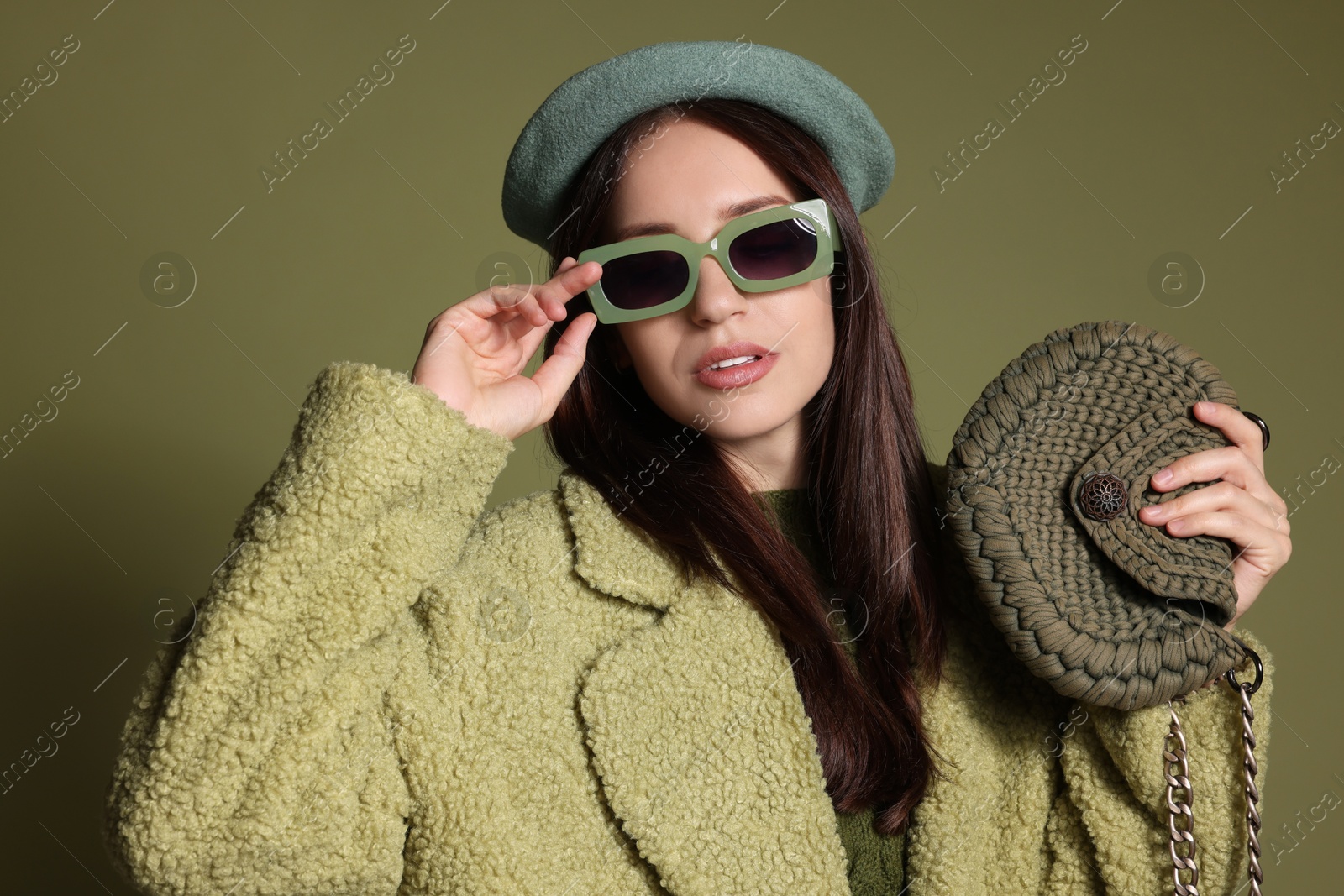 Photo of Young woman with stylish accessories on olive background