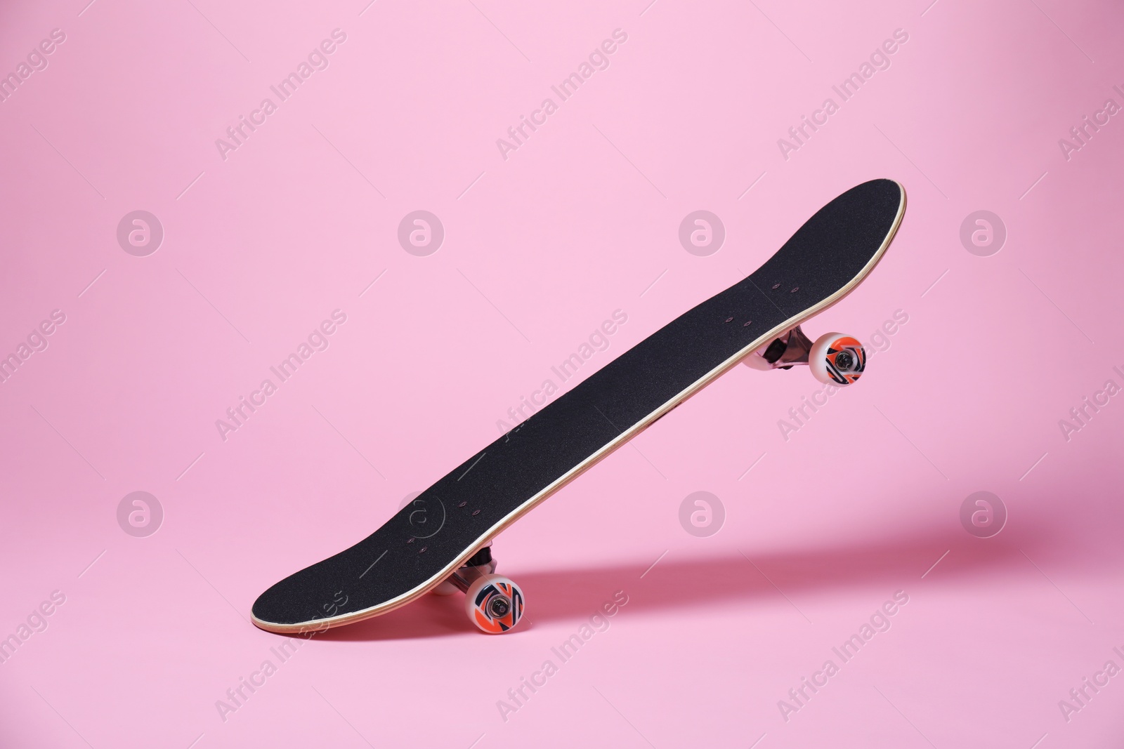 Photo of One skateboard on pink background. Sports equipment