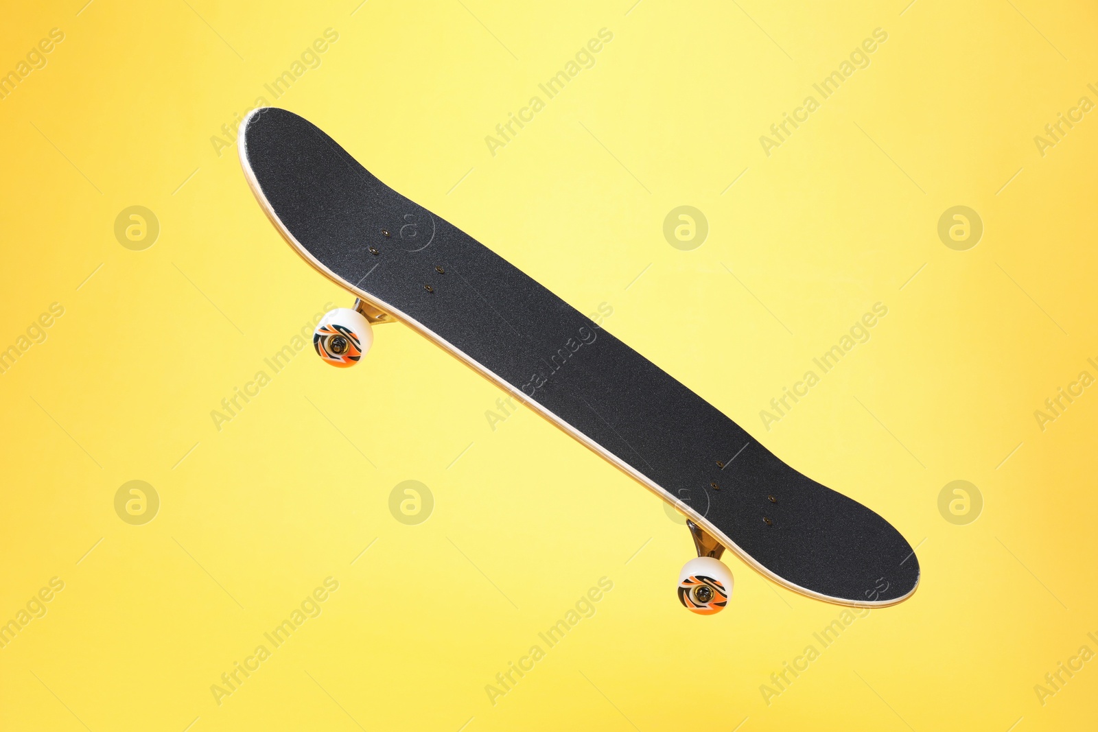 Photo of One skateboard on yellow background. Sports equipment