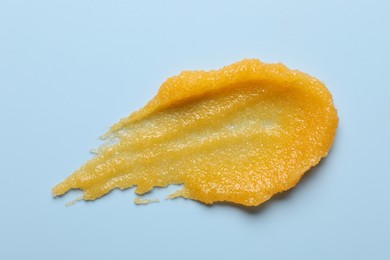 Photo of Smear of body scrub on light blue background, top view