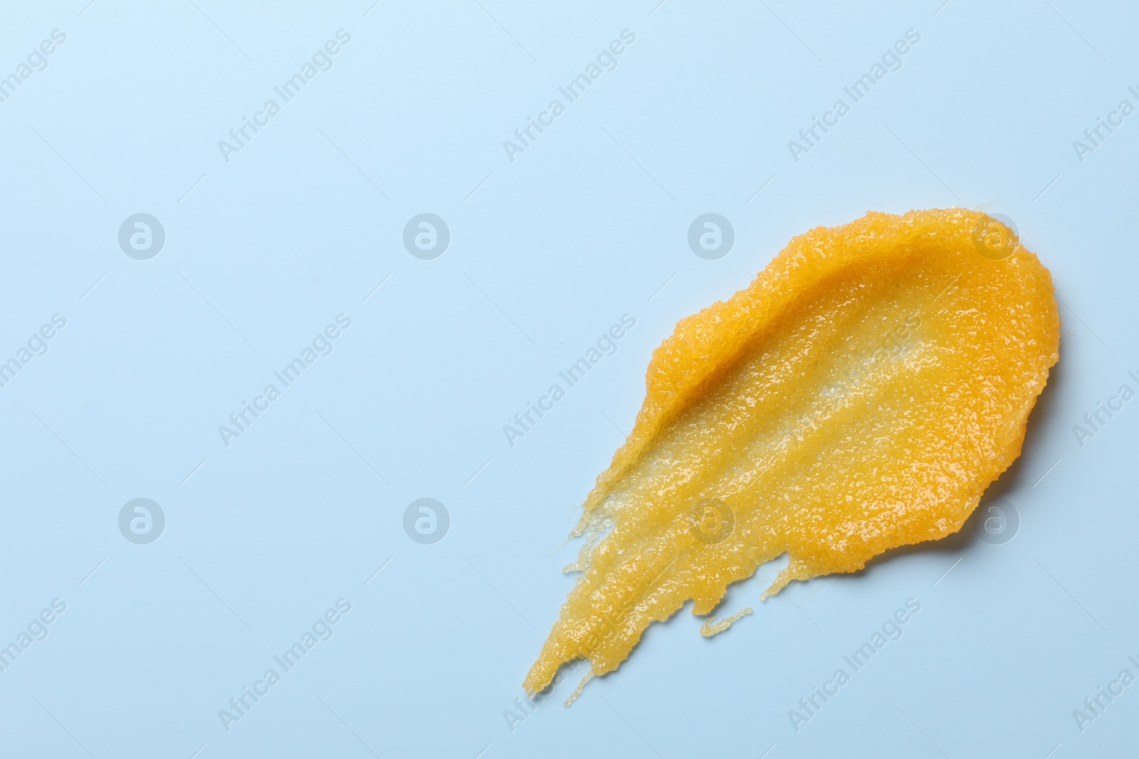 Photo of Smear of body scrub on light blue background, top view. Space for text