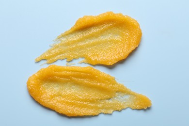 Photo of Smears of body scrub on light blue background, top view