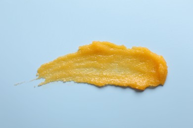 Photo of Smear of body scrub on light blue background, top view