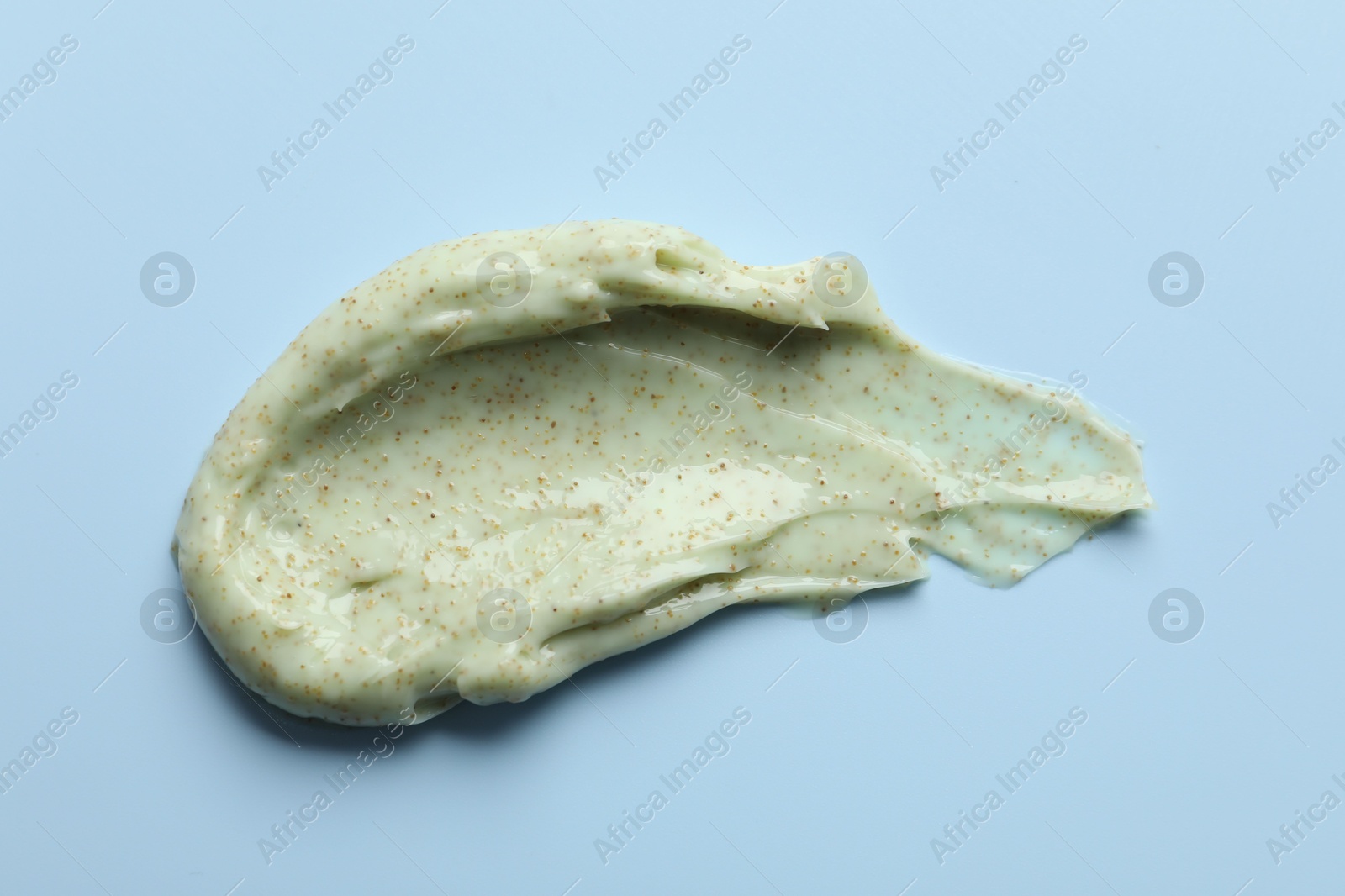 Photo of Smear of body scrub on light blue background, top view