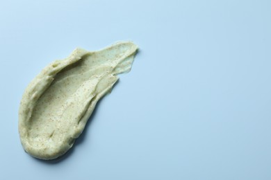 Photo of Smear of body scrub on light blue background, top view. Space for text