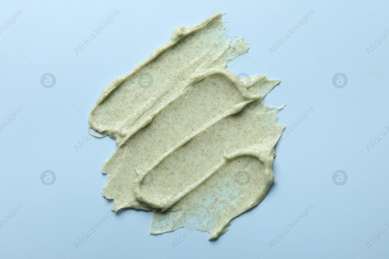 Photo of Smears of body scrub on light blue background, top view