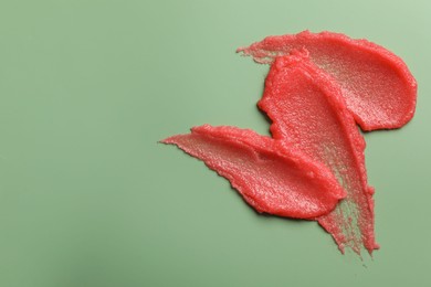 Photo of Smears of body scrub on light green background, top view. Space for text