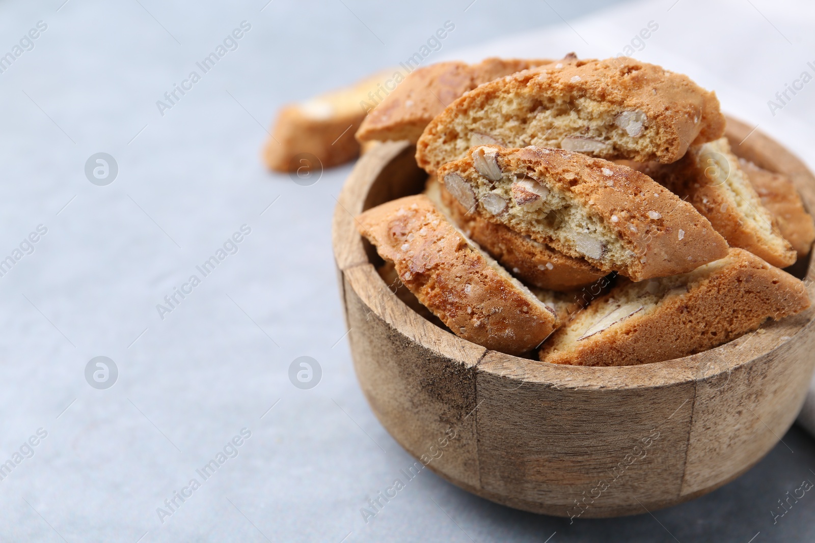 Photo of Traditional Italian almond biscuits (Cantucci) in bowl on grey table, closeup. Space for text