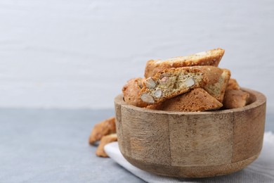 Photo of Traditional Italian almond biscuits (Cantucci) in bowl on grey table, closeup. Space for text