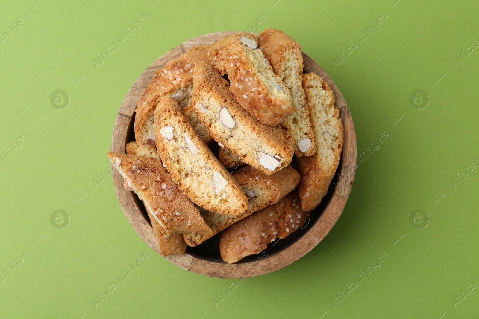 Photo of Traditional Italian almond biscuits (Cantucci) in bowl on green background, top view