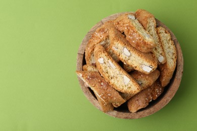 Photo of Traditional Italian almond biscuits (Cantucci) in bowl on green background, top view. Space for text