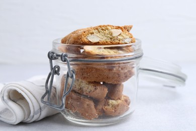 Photo of Traditional Italian almond biscuits (Cantucci) in jar on light table, closeup