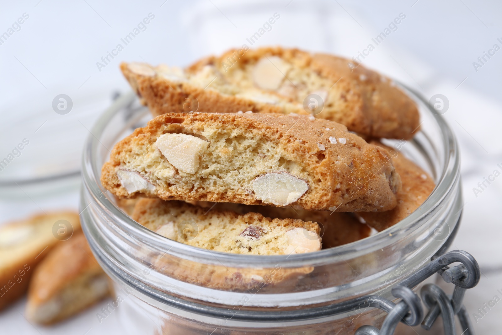 Photo of Traditional Italian almond biscuits (Cantucci) in jar on white table, closeup