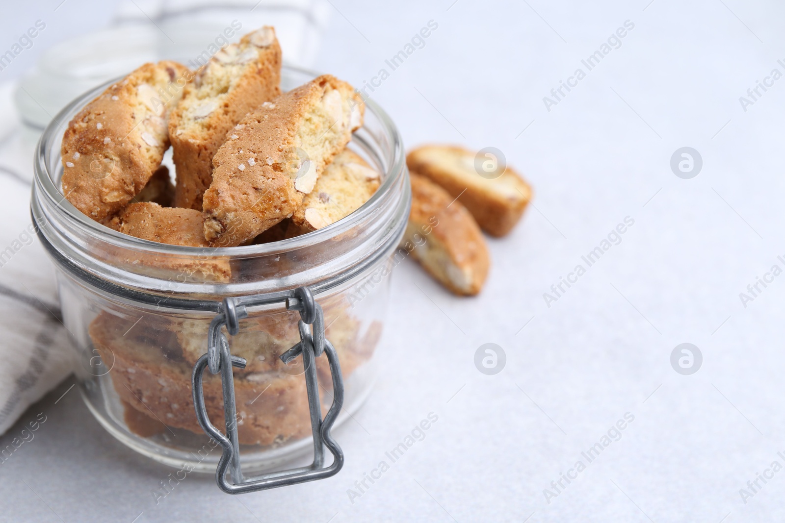 Photo of Traditional Italian almond biscuits (Cantucci) in jar on light table, closeup. Space for text