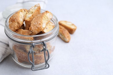 Photo of Traditional Italian almond biscuits (Cantucci) in jar on light table, closeup. Space for text