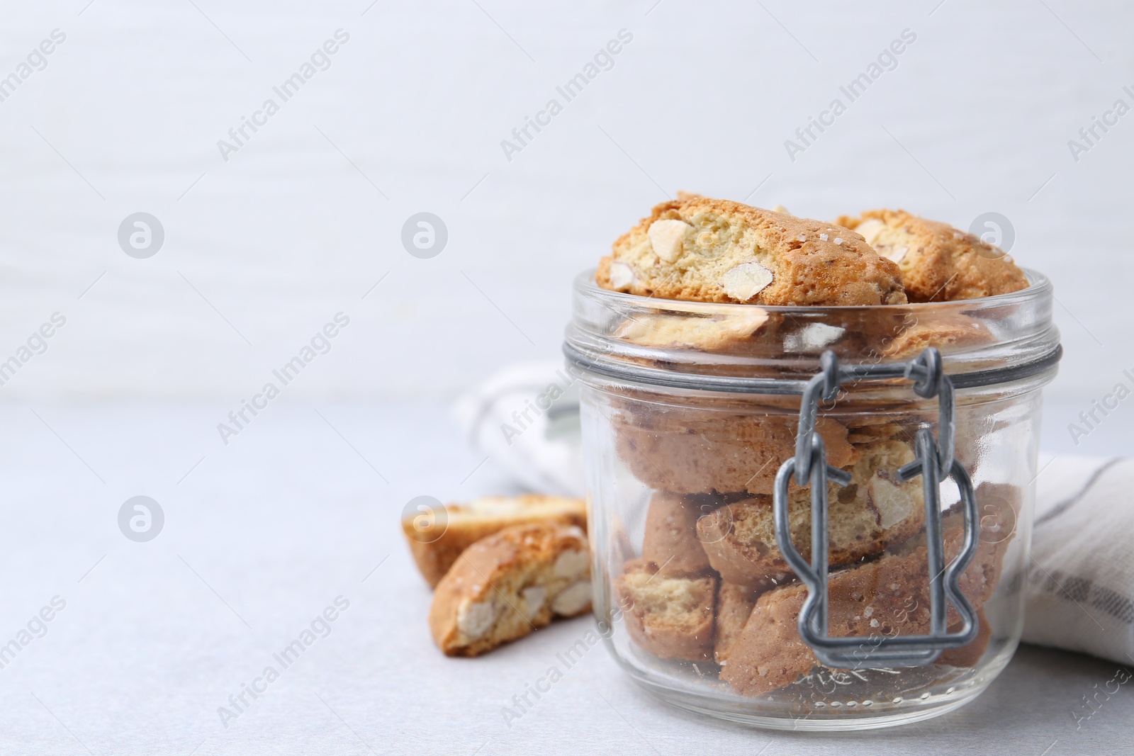 Photo of Traditional Italian almond biscuits (Cantucci) in jar on light table, closeup. Space for text