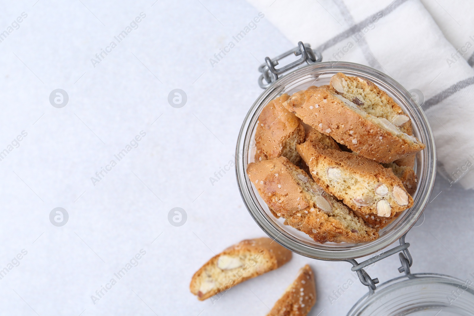 Photo of Traditional Italian almond biscuits (Cantucci) in jar on light table, top view. Space for text