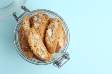 Photo of Traditional Italian almond biscuits (Cantucci) in jar on turquoise background, top view