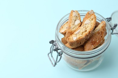 Photo of Traditional Italian almond biscuits (Cantucci) in jar on turquoise background, closeup. Space for text