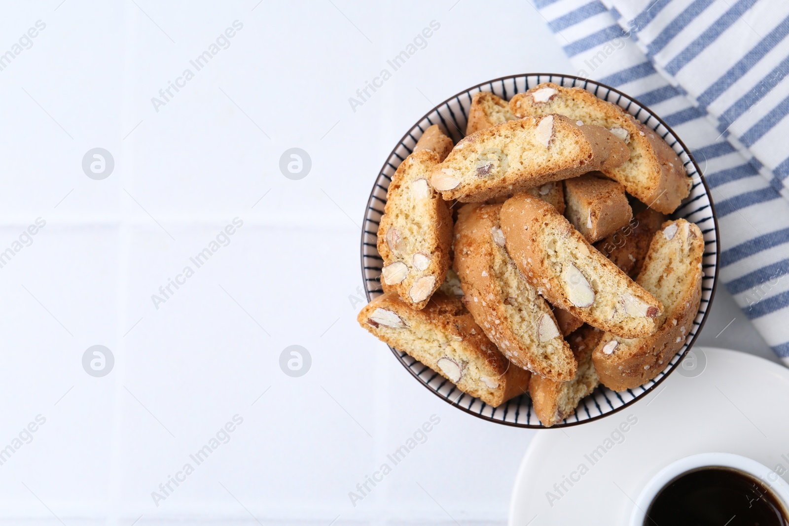 Photo of Traditional Italian almond biscuits (Cantucci) in bowl on white table, top view. Space for text