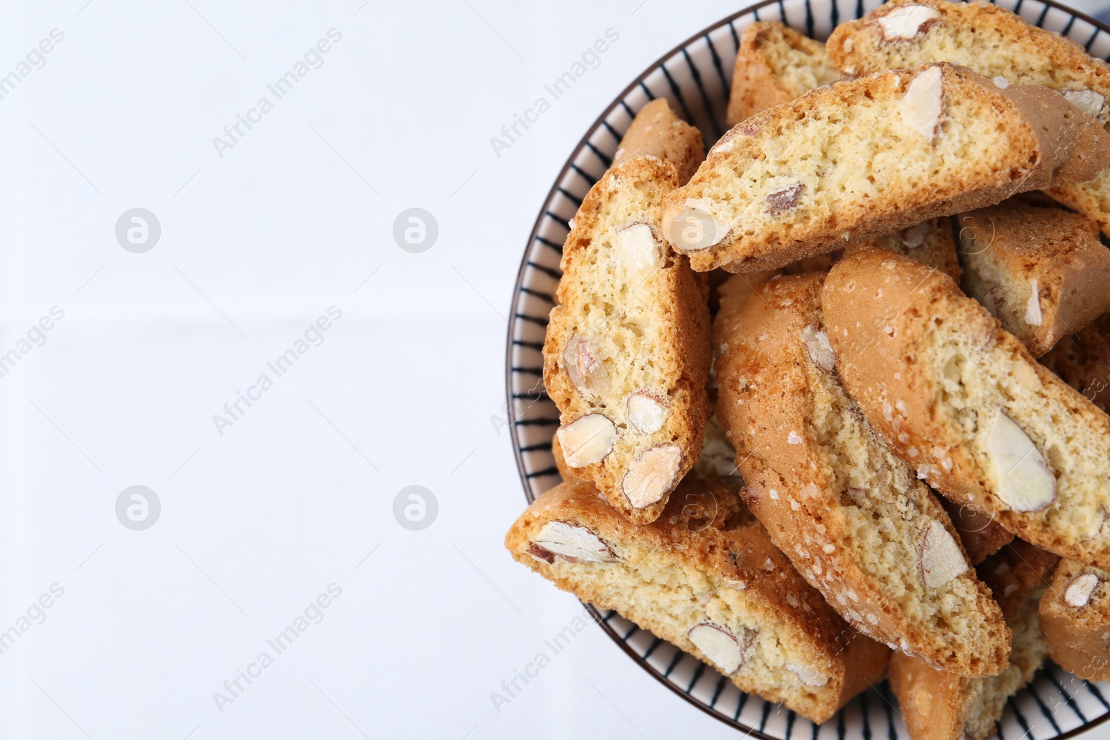 Photo of Traditional Italian almond biscuits (Cantucci) in bowl on white table, top view. Space for text