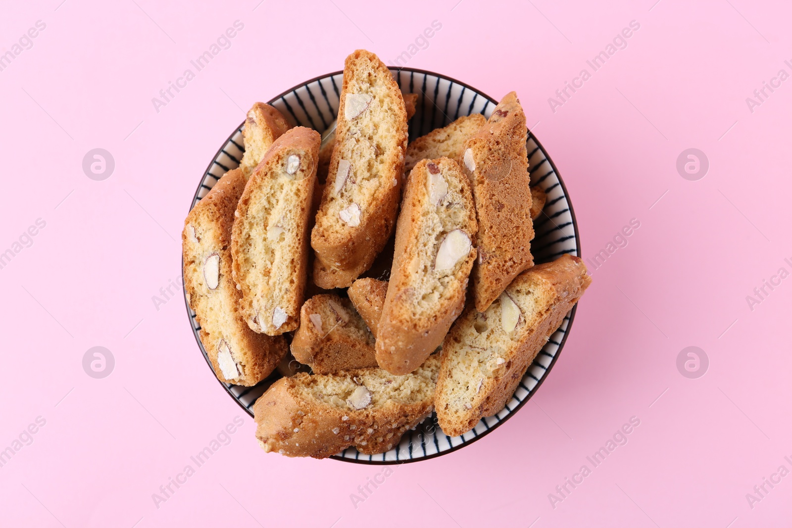 Photo of Traditional Italian almond biscuits (Cantucci) in bowl on pink background, top view