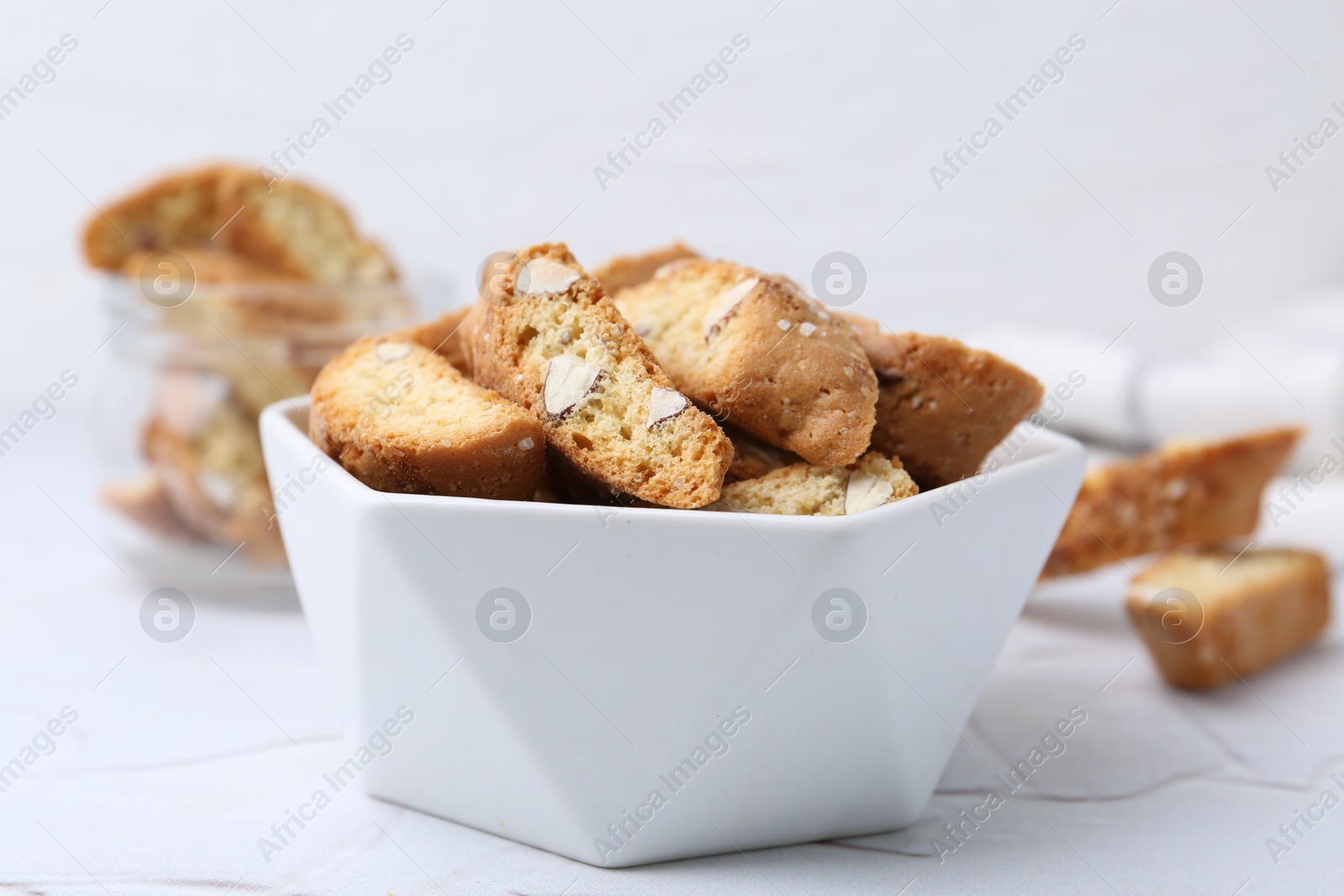 Photo of Traditional Italian almond biscuits (Cantucci) in bowl on white table, closeup