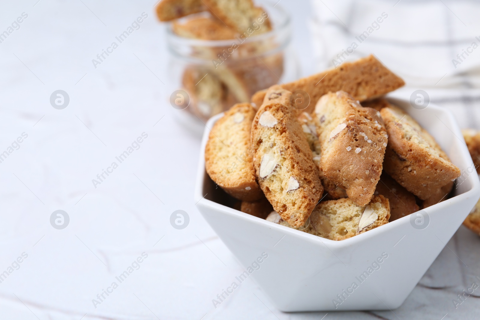 Photo of Traditional Italian almond biscuits (Cantucci) in bowl on white table, closeup. Space for text