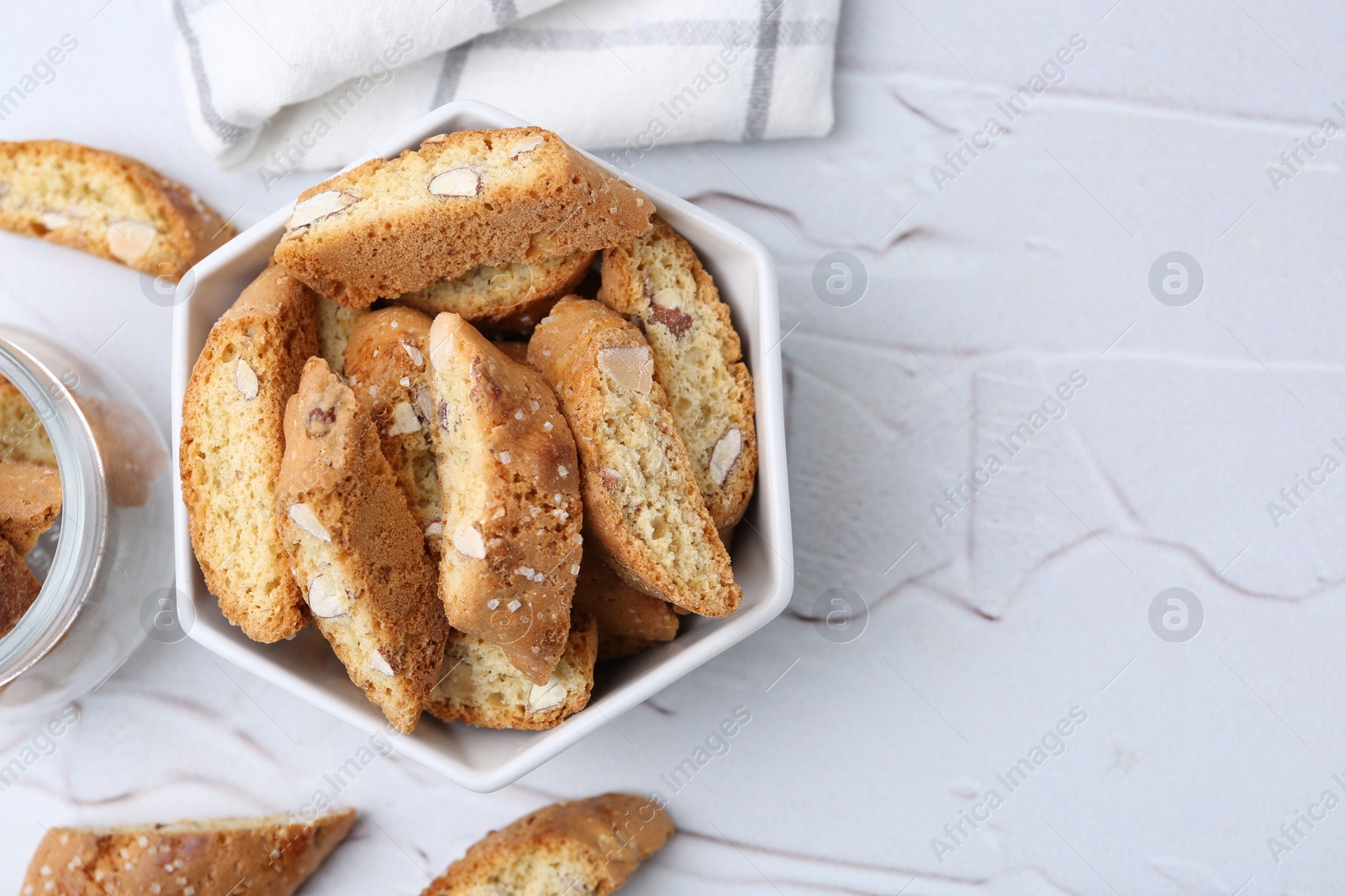 Photo of Traditional Italian almond biscuits (Cantucci) in bowl on white table, top view. Space for text