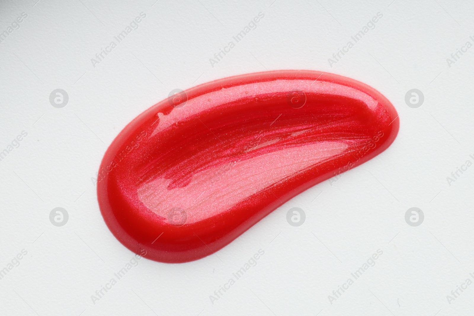 Photo of Red lip gloss isolated on white, top view. Sample of cosmetic product