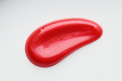 Photo of Red lip gloss isolated on white, top view. Sample of cosmetic product