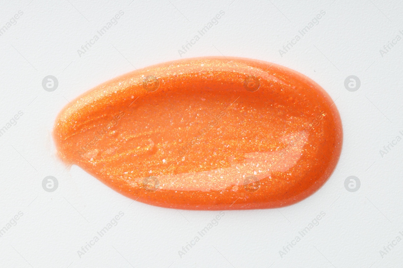 Photo of Orange lip gloss isolated on white, top view. Sample of cosmetic product