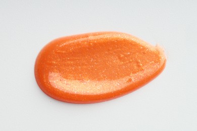 Photo of Orange lip gloss isolated on white, top view. Sample of cosmetic product