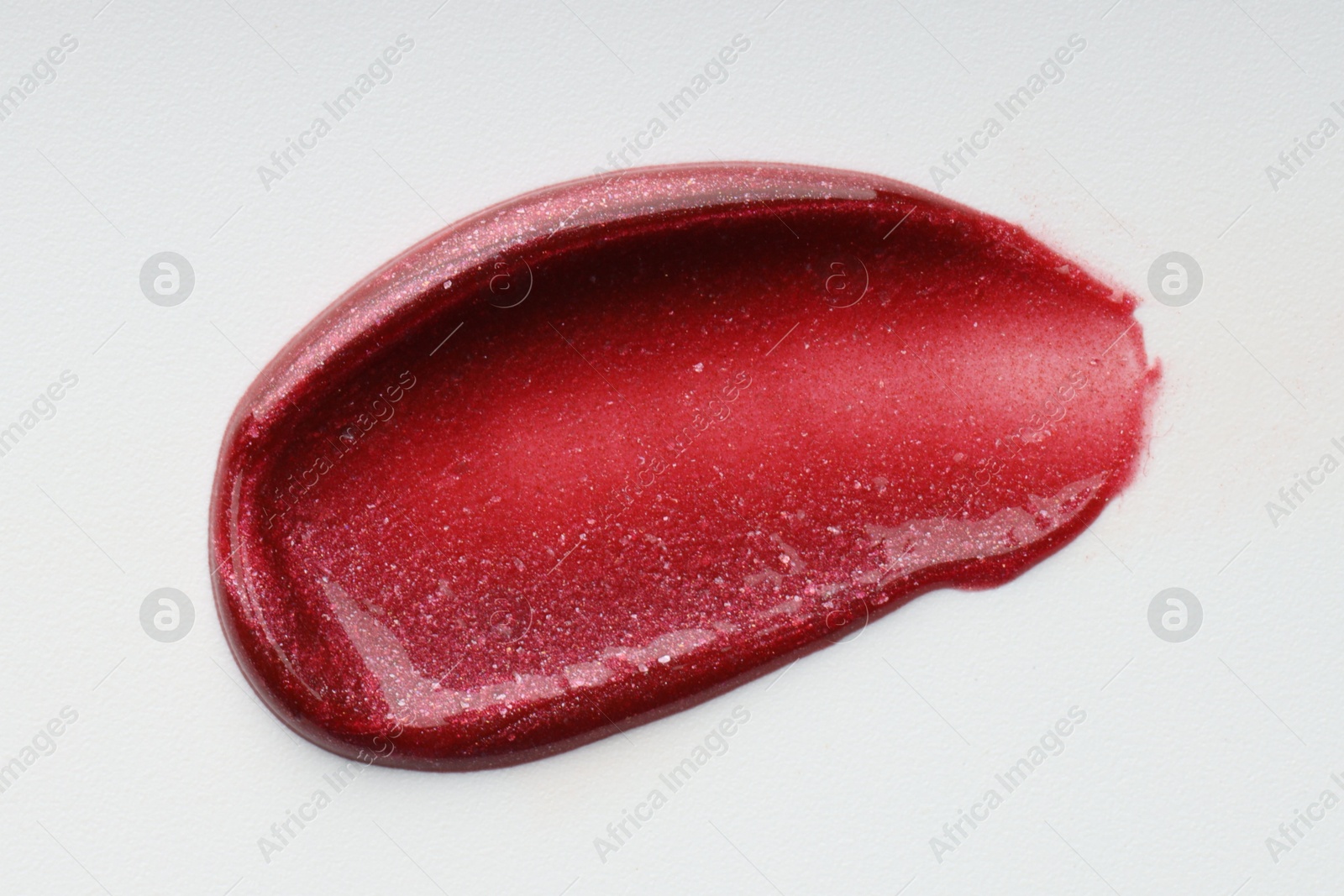 Photo of Bright lip gloss isolated on white, top view. Sample of cosmetic product