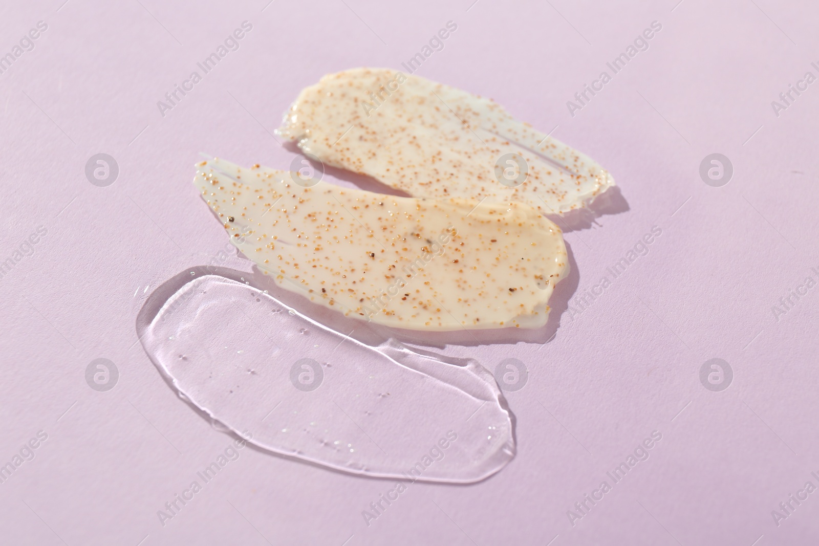 Photo of Samples of cosmetic products on light violet background, closeup. Skin care