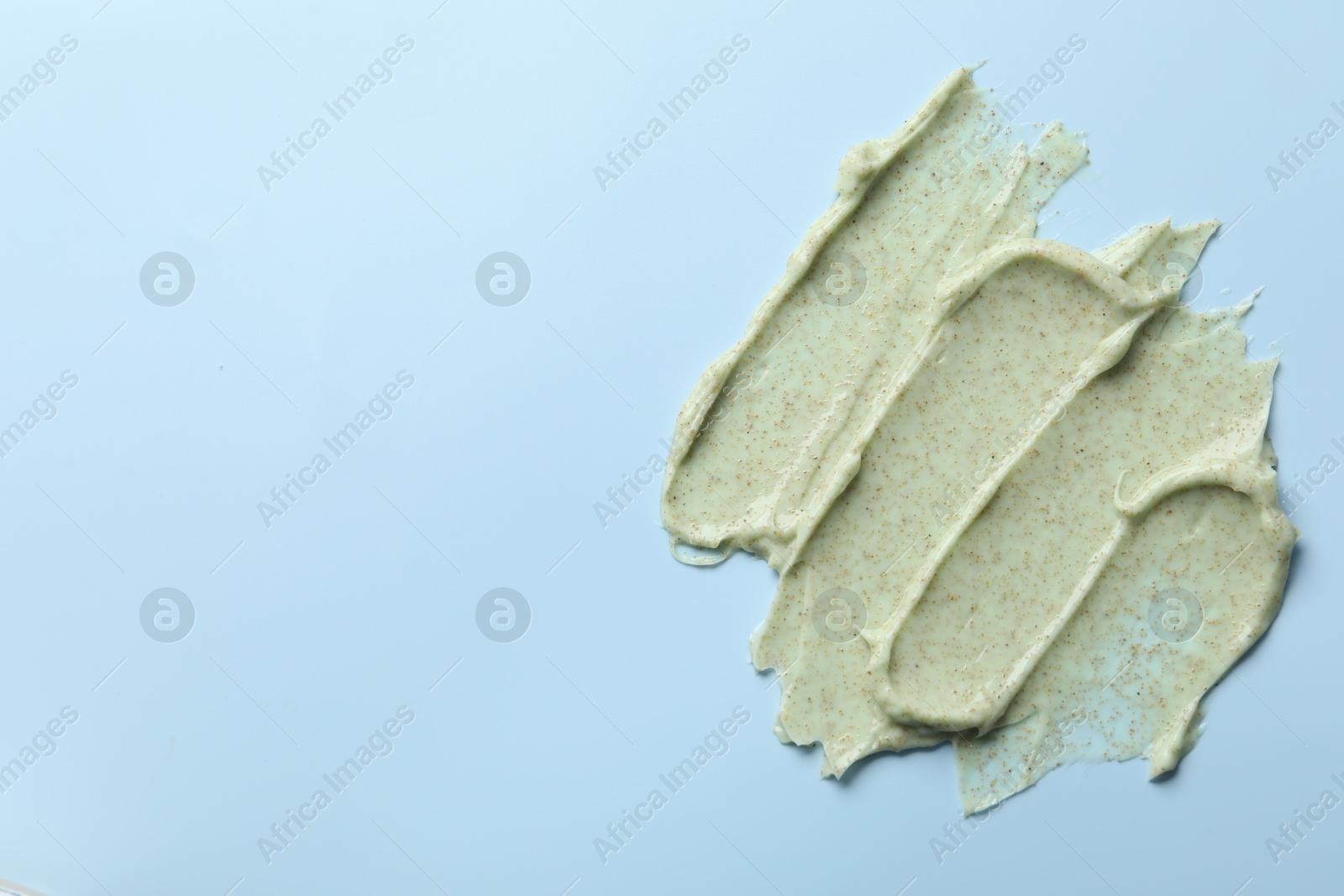 Photo of Smears of body scrub on light blue background, top view. Space for text