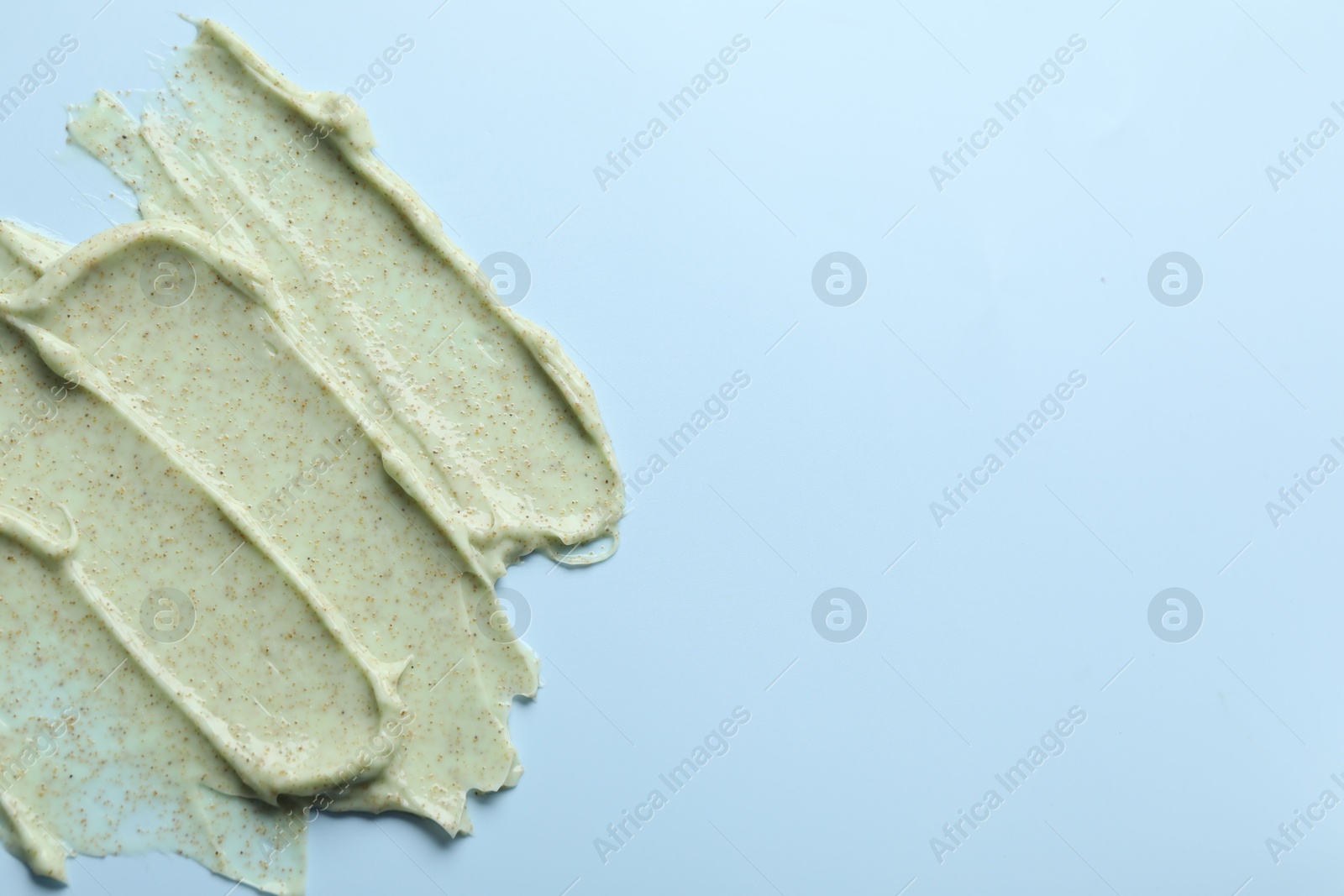 Photo of Smears of body scrub on light blue background, top view. Space for text