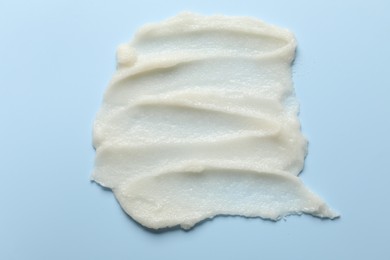 Photo of Smears of natural body scrub on light blue background, top view