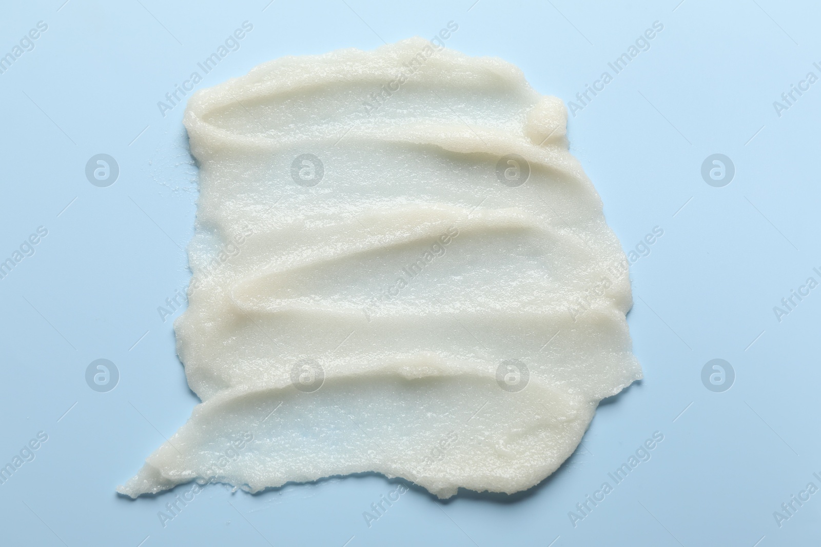 Photo of Smears of natural body scrub on light blue background, top view