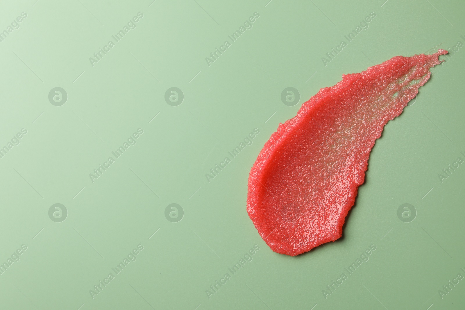 Photo of Smear of body scrub on light green background, top view. Space for text