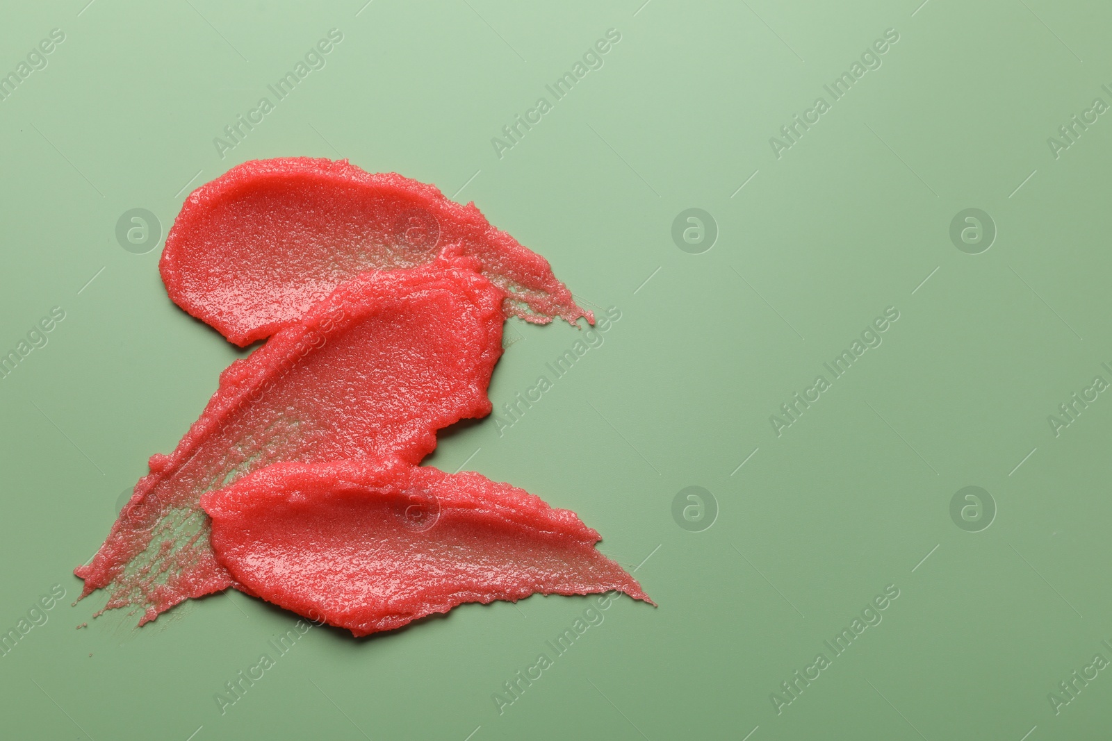 Photo of Smears of body scrub on light green background, top view. Space for text