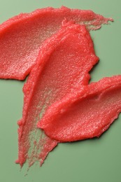 Photo of Smears of body scrub on light green background, top view