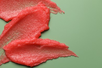 Photo of Smears of body scrub on light green background, top view. Space for text