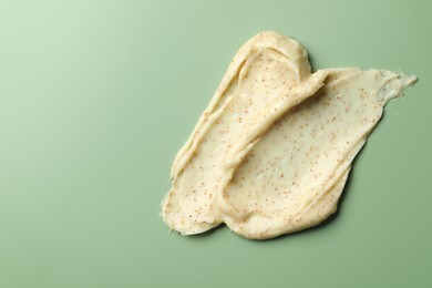 Photo of Smears of body scrub on light green background, top view. Space for text