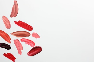 Photo of Smears of different lip products on white background, top view